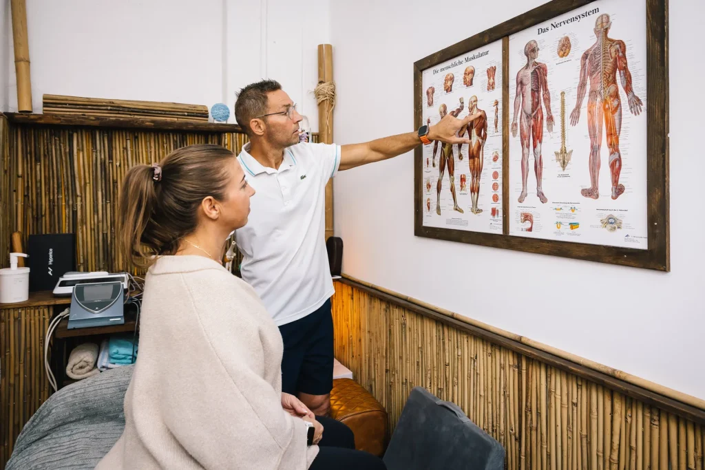 Stefan Hornburg erklärt einer Kundin den Körper an einer anatomischen Schautafel
