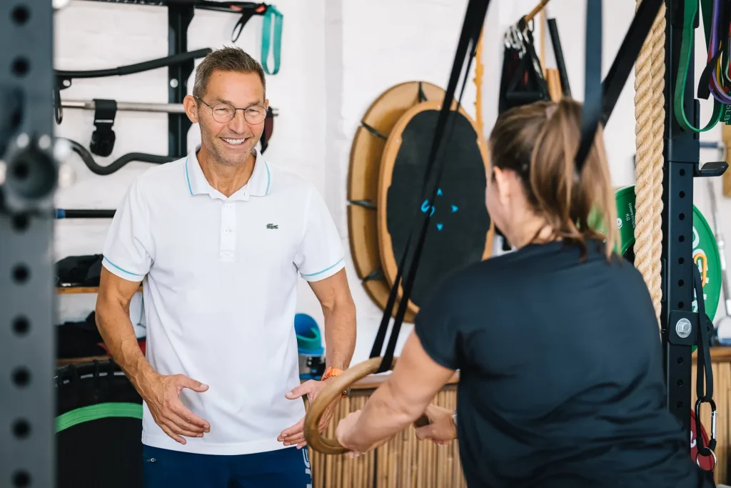 Stefan Hornburg im Studio mit einer Kundin an den Turnringen